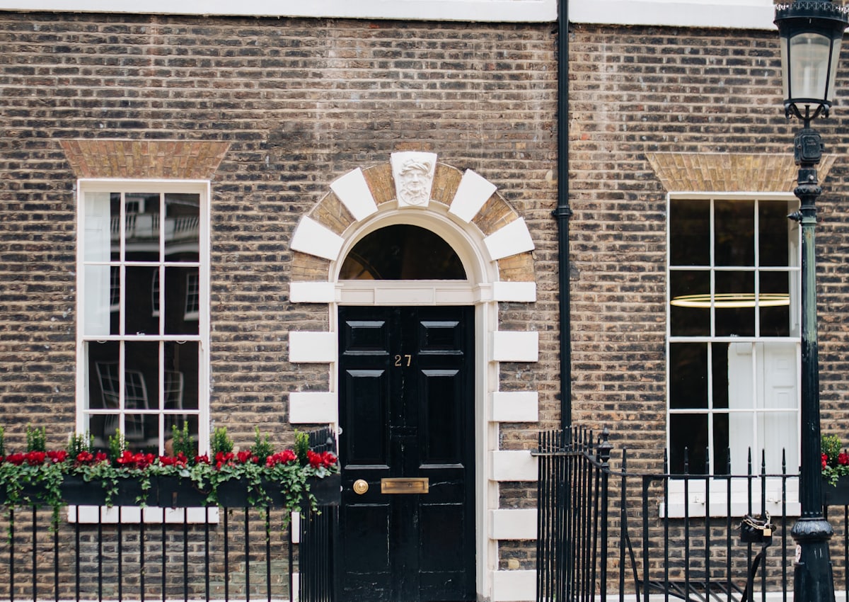 Black panelled front door with a fanlight on a yellow brick townhouse