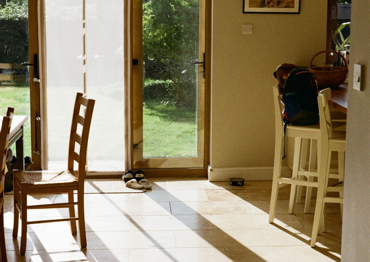 Kitchen diner with glazed doors standing open onto a sunlit lawn