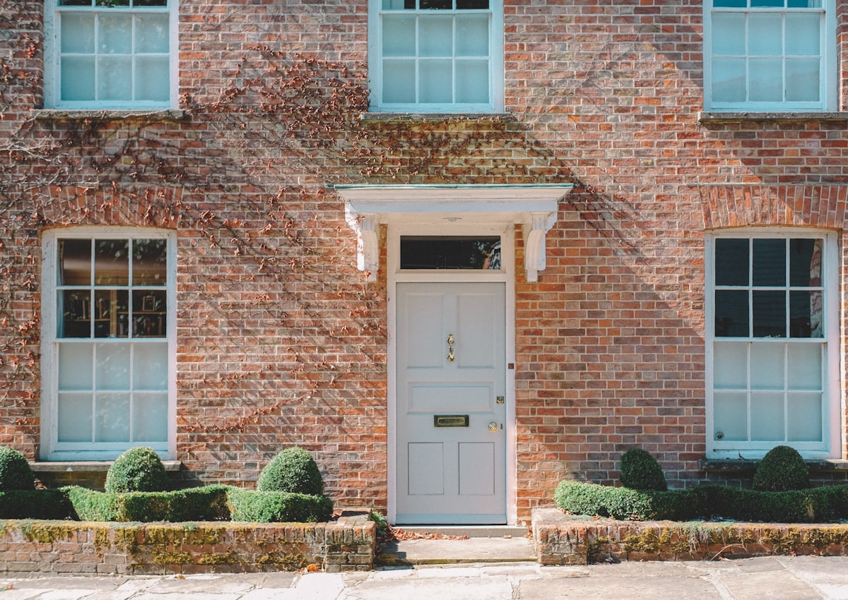 Painted front door set into a red brick elevation with sash windows