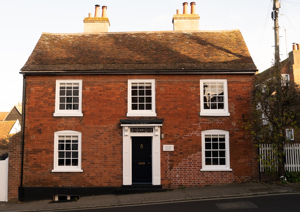 English red brick house with white sash windows and a black front door in evening light